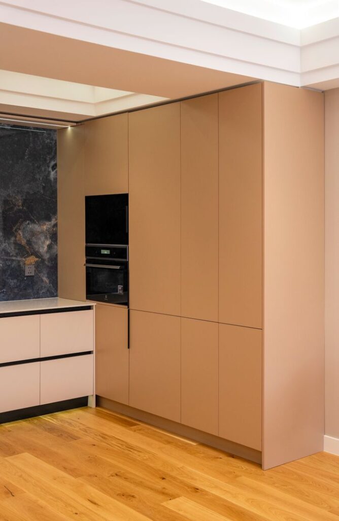 Sleek modern kitchen design featuring beige cabinetry, integrated appliances, and wooden flooring.