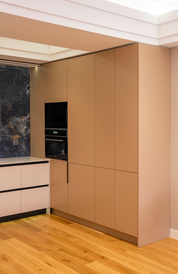 Sleek modern kitchen design featuring beige cabinetry, integrated appliances, and wooden flooring.