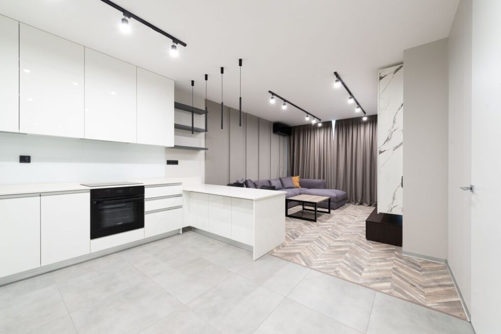 Sleek open-plan kitchen and living area with contemporary design featuring white cabinets and neutral tones.