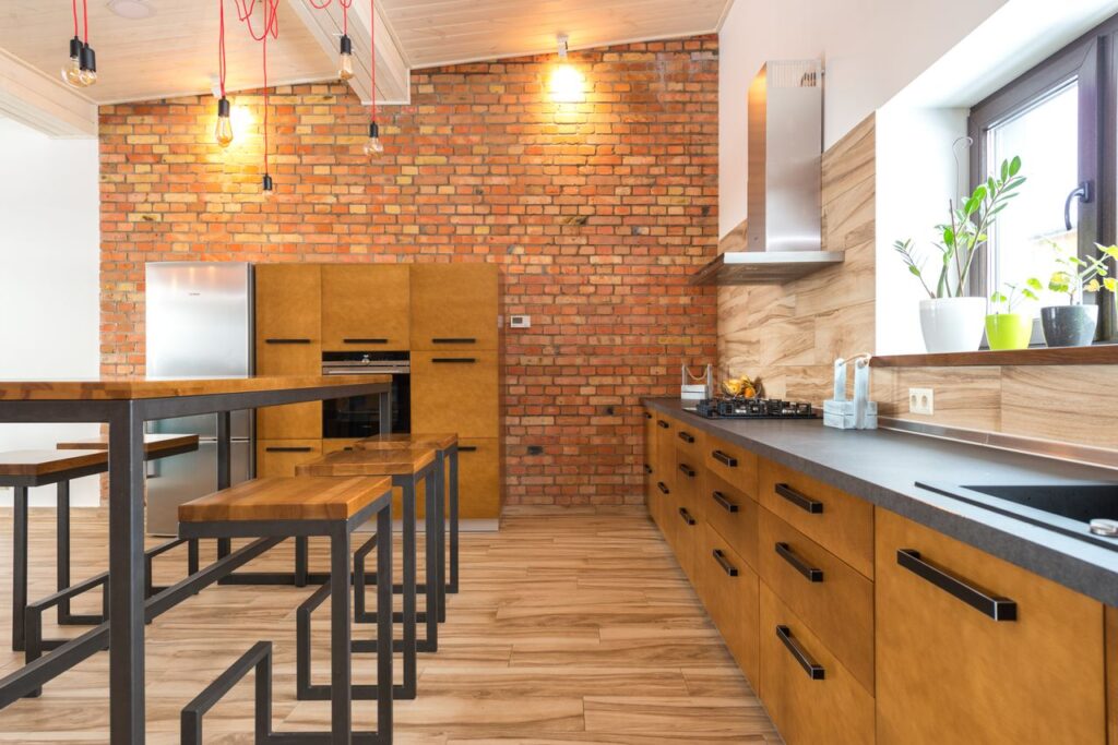Contemporary kitchen featuring brick wall, wooden cabinets, and sleek design elements with ample natural light.